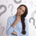 Mujer pensativa con signos de interrogación, simbolizando la confusión entre infección urinaria y candidiasis